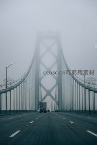 浓雾中的海湾大桥高速路，车辆穿行于钢铁巨构之间，宛如科幻场景