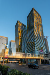 金色夕照映照现代摩天双塔，玻璃幕墙流光溢彩，都市脉搏跃动