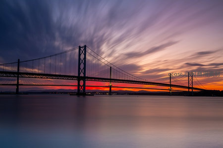 旧金山奥克兰海湾大桥日落长曝，彩霞流云如丝带横跨水面