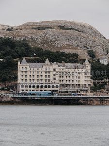 海滨悬崖下的宏伟酒店建筑，灰白石墙与山体相映成趣