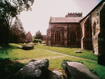 古老教堂庭院静谧午后，哥特窗棂与青草墓碑相映