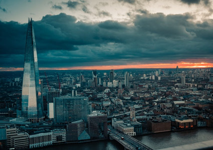 碎片大厦耸立伦敦天际线，暴风云隙透出橙红晚霞，泰晤士河蜿蜒穿城
