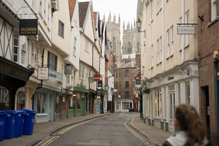 约克古城窄巷尽头耸立大教堂尖顶，店铺林立烟火气十足