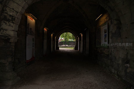 古老石拱廊道幽暗深邃，尽头绿意微光透出宁静庭院