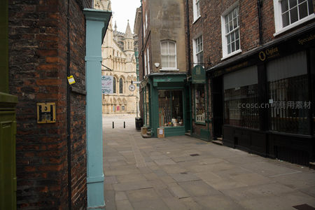 窄巷尽头窥见约克大教堂，青绿色门框与老店招牌点缀古韵