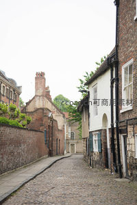 蜿蜒鹅卵石小巷，白墙黑管老屋与红砖墙交织的中世纪风貌