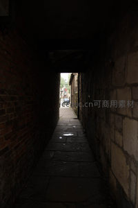 幽深砖石小巷尽头透光，光影对比强烈，神秘古老巷道探秘视角