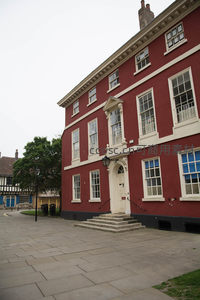 鲜红乔治亚风格府邸，白色窗框与门廊典雅精致，庭院绿树映衬庄重气派