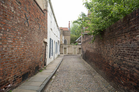 狭窄鹅卵石巷道夹于红砖老墙之间，尽头隐现古典门窗与绿植点缀