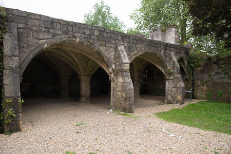 石砌拱廊通道遗迹，粗犷柱墩支撑连续尖券，碎石地面诉说昔日功能