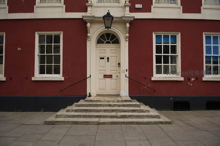 红色外墙古典建筑正门，白色门廊配扇形窗与石阶，庄重典雅具历史感