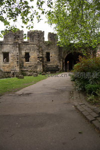 绿荫掩映下的古老石砌城门遗迹，青草铺地，静谧悠远