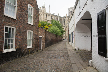 窄巷尽头仰望约克大教堂，红砖墙与白墙拱廊构成经典英伦街景