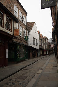 约克肉铺街商铺林立，复古招牌悬于斜坡石巷，雨后微光映照古韵