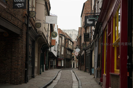 约克古城窄巷石板路，两侧砖墙老店招牌林立，静谧历史氛围浓厚