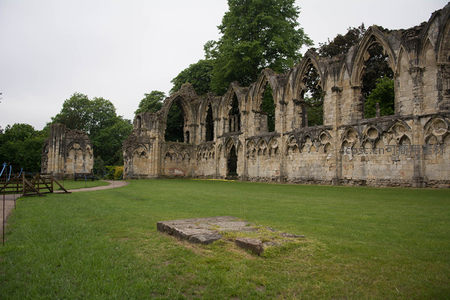 约克修道院高耸哥特窗框遗迹，绿茵环绕，古墙与参天树影交织成画