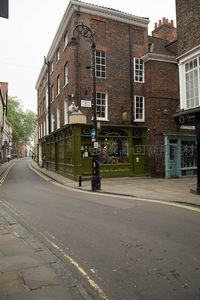约克街角绿色店铺转角楼，铸铁路灯与砖墙相映，典型英伦商业街景