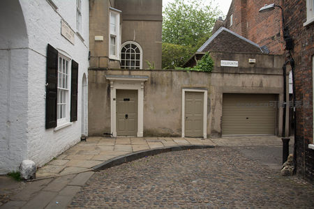 白墙黑窗巷角转角，鹅卵石路衔接古典门廊与车库，新旧交融街景