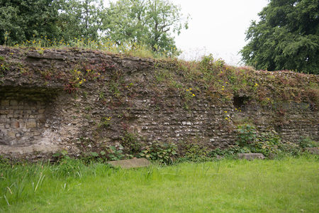 长段古罗马城墙遗存，青苔覆顶野草蔓延，绿茵前显沧桑岁月痕迹