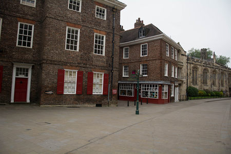 红砖联排建筑配朱红百叶窗，街角小店与哥特教堂遥相呼应