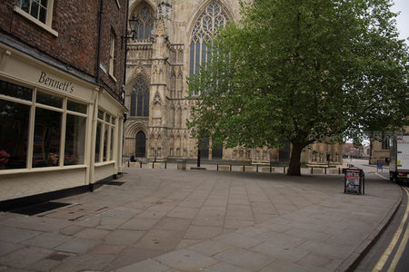 约克大教堂前街景，绿树掩映古建筑与商铺招牌