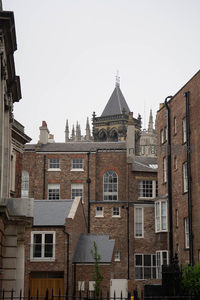 红砖建筑群间窥见哥特式教堂尖塔，古典屋顶与现代窗框交织的城市肌理