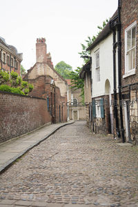 蜿蜒鹅卵石小巷通向幽深院落，白墙黑管与砖墙绿植相映成趣的静谧角落