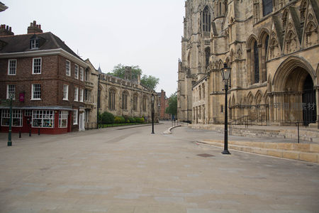 空旷广场前矗立约克大教堂西立面，哥特雕饰精美，旁侧红砖商铺静默守候