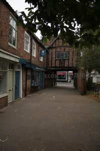 约克肉铺街老巷景致，木构架房屋与砖墙交织，绿叶掩映古朴街巷