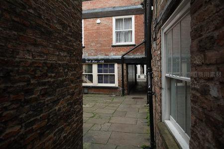 红砖巷弄中的艺术画廊入口，透过砖墙缝隙窥见庭院静景