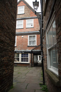 砖墙夹缝中的老宅庭院，古典窗棂与街灯共构英伦风情画面