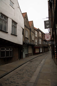 约克肉铺街侧巷，都铎式木构屋檐下悬挂复古招牌与铁艺灯饰