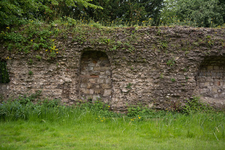 罗马城墙遗迹嵌入绿野，荒草丛生的拱形壁龛诉说着帝国余晖