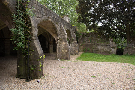 古老石拱廊遗迹静卧绿茵间，藤蔓攀爬柱体，碎石铺地显沧桑