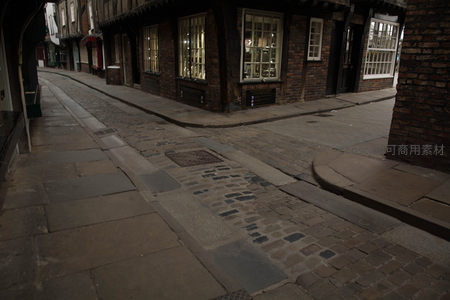 黄昏时分空寂古街转角，暖光窗棂与冷调石板路形成光影对比