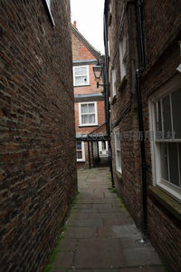 狭窄砖墙小巷，石板路延伸至古老建筑深处