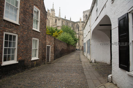 约克大教堂尖塔隐现于红砖巷尾，绿树点缀古巷尽头