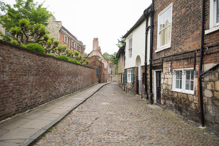 约克肉铺街旁鹅卵石小径蜿蜒，红砖墙与修剪绿植相映成趣