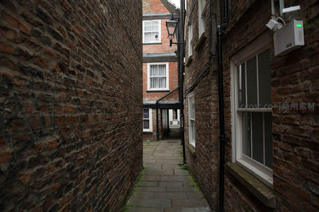约克砖墙夹缝小径纵深透视，监控摄像头与老窗形成时代对比