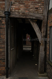 木构过街廊道暗影幽深，老旧砖墙与粗犷梁柱交织