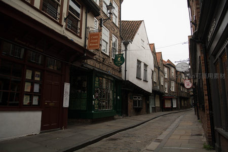 约克古城窄巷清晨静谧街景，砖石建筑与复古招牌相映成趣