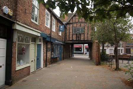 木构架过街楼连接老街巷，绿叶掩映下展现约克中世纪街巷肌理