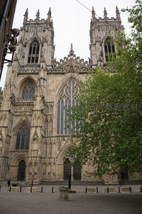 约克大教堂西立面全景，哥特尖塔与绿树相映