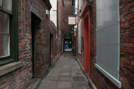 红砖窄巷幽深静谧，门廊斑驳，尽头透出一抹蓝光，充满故事感