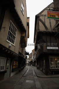 狭窄中世纪鹅卵石小巷，木筋墙房屋林立，招牌悬垂显古韵