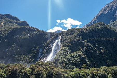 雄伟峡湾瀑布从险峻山脊奔涌而下，云影掠过苍翠峰峦