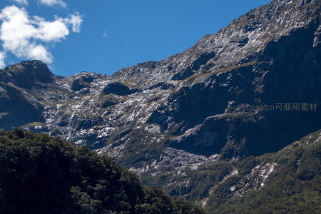 阳光照耀下层峦叠嶂的灰岩山体，局部覆雪，林带分明