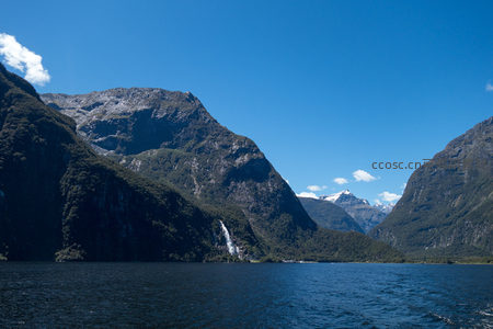 峡湾侧翼小瀑布隐现林间，主峰雄踞，远山雪顶辉映晴空