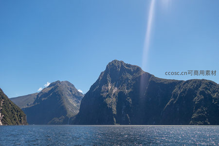 阳光穿透云隙洒向峡湾主峰，瀑布隐现山腰，碧海映衬苍翠峰林