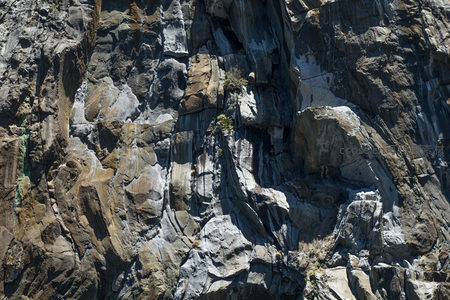 阳光照射下的断层岩壁特写，矿物脉络清晰可见